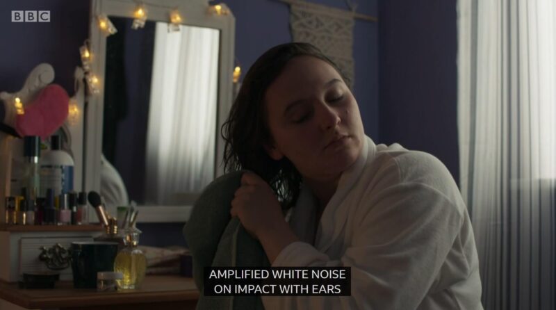 Clip of Casualty episode where Jade is in her bedroom, sitting in front of her dressing table and drying her wet hair with a towel and the caption at the bottom is "Amplified white noise on impact with ears"